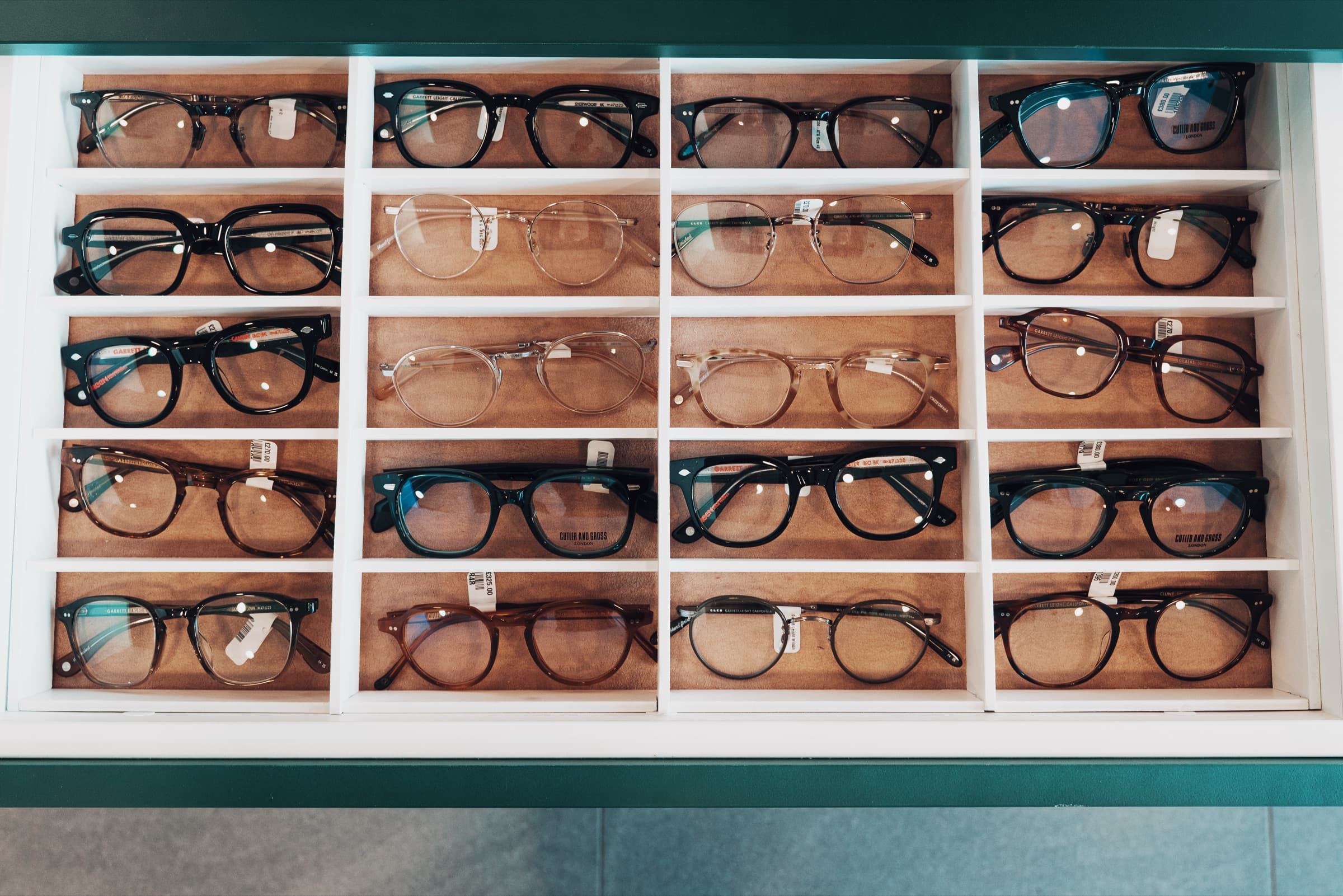 Top-down grid of black acetate frames in white display cubbies